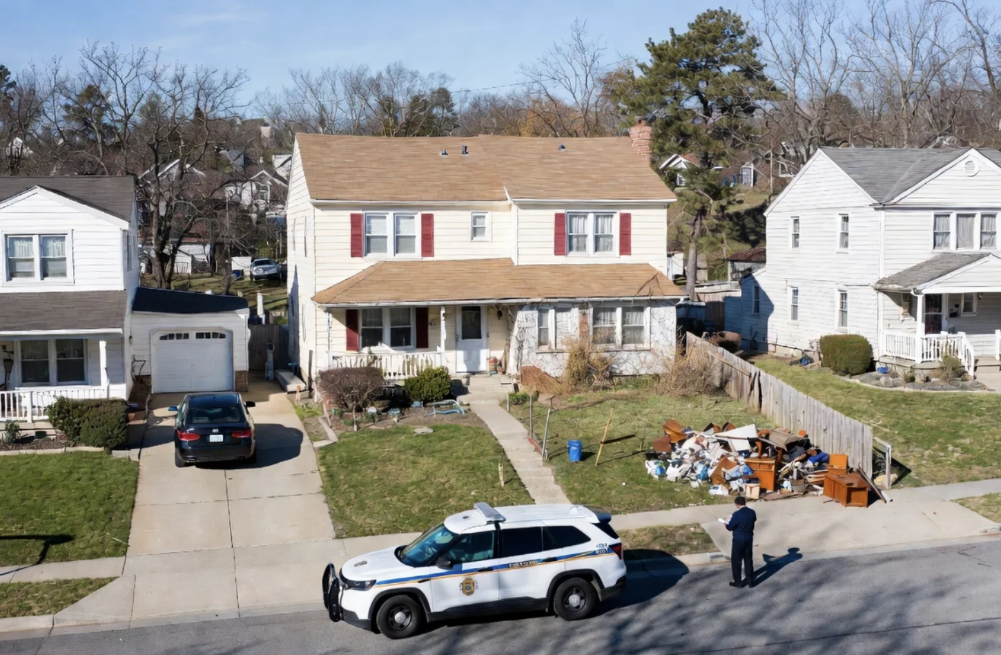 A code enforcement officer documenting a debris pile in a front yard from the street