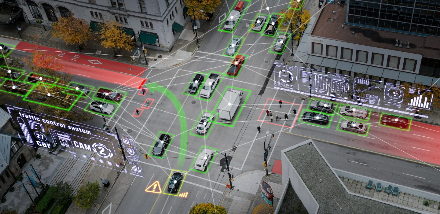An intersection seen from above with AI detection boxes over vehicles and pedestrians